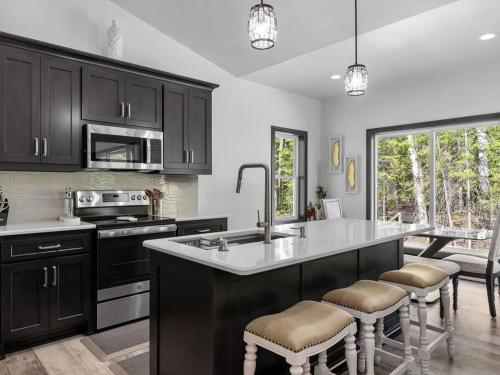 a kitchen with black cabinets and a kitchen island with bar stools at New, charming custom home in Sturgeon Bay