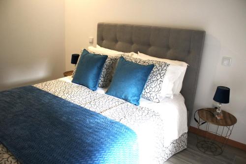 a bedroom with a large bed with blue pillows at Casa da Carrasqueira in Soajo