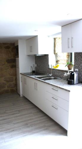 a kitchen with white cabinets and a counter top at Casa da Carrasqueira in Soajo