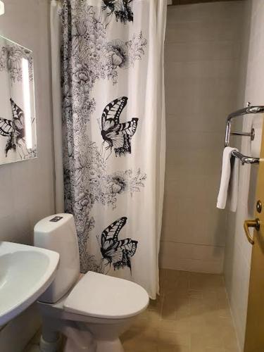 a bathroom with a toilet and a shower curtain with butterflies at Hotelli Viikinhovi in Keuruu