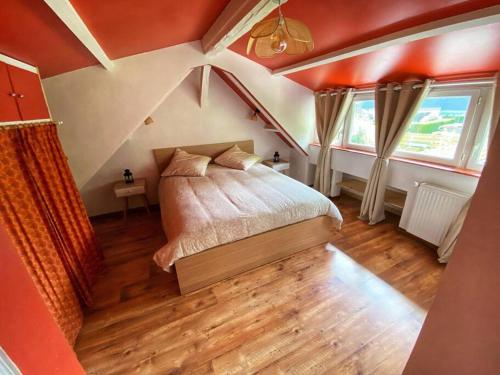 una camera da letto con letto, pareti arancioni e pavimenti in legno di Le Mesnil Champêtre a Ouville-la-Rivière