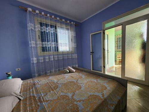 a blue bedroom with a bed and a window at Villa Orange in Vlorë