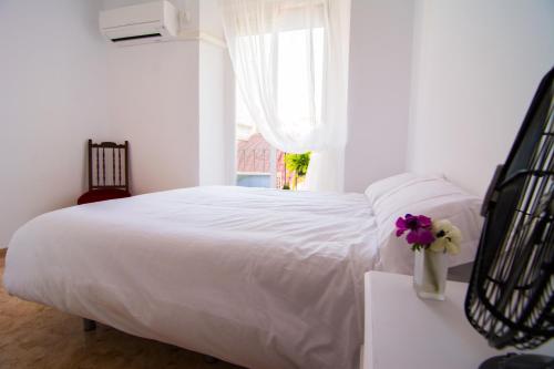 1 dormitorio con 1 cama blanca y un jarrón de flores en San José Guest House, en Granada