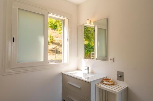 La salle de bains blanche est pourvue d'un lavabo et d'une fenêtre. dans l'établissement Domaine Bagia Donne, à Santa-Reparata-di-Balagna