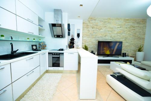 a kitchen with white cabinets and a living room at Hana apartament hot tub in Vlorë