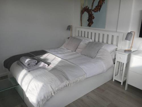 a white bed in a bedroom with a night stand at Brighton Boutique Garden Studio with Free Parking in Brighton & Hove