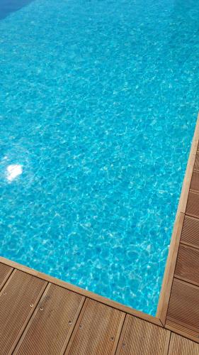 a large pool of blue water next to a wooden deck at Villa Capitani in Torre Canne