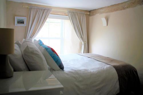 a bedroom with a white bed with a window at The Roost - Askrigg 18th Century Cottage in Askrigg