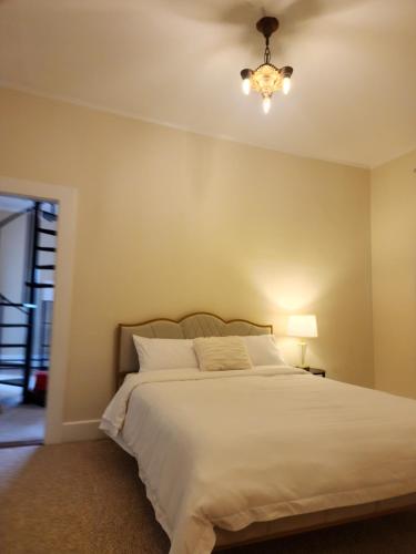 a bedroom with a large white bed with a chandelier at Island View House BnB Self Check-In in Portland