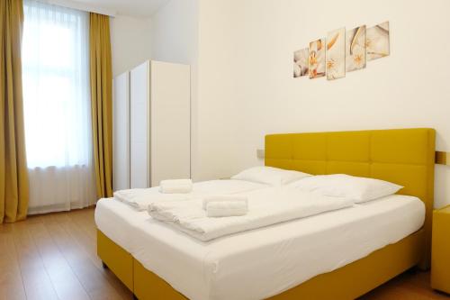 1 dormitorio con 1 cama blanca grande y cabecero amarillo en Apartments 4 you Red Star 8, en Viena