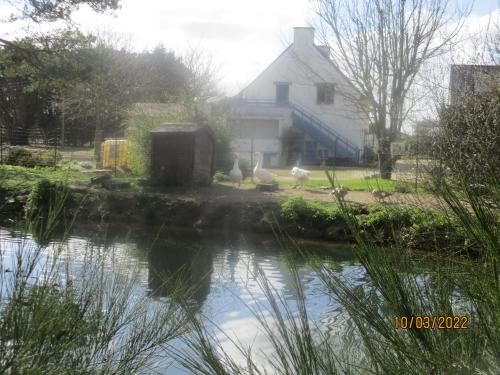 Garlan的住宿－CAMPING VERT DE MORLAIX，房屋前的房屋和池塘