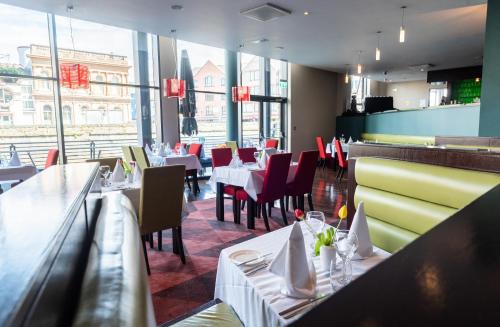 a restaurant with white tables and red chairs at The Glasshouse in Sligo