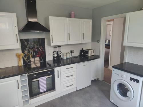 a kitchen with white cabinets and a washing machine at Bexhill Stunning 2 bedroom Sea Front Bungalow in Bexhill