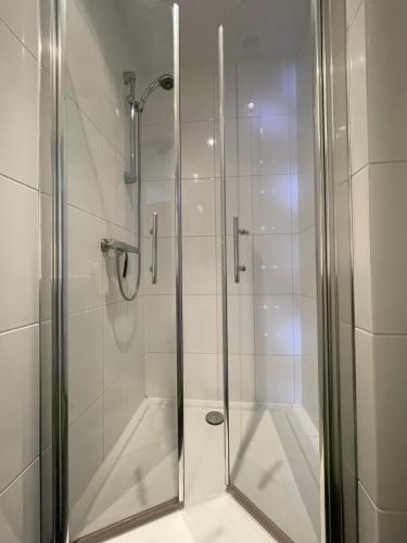 een douche met een glazen deur in de badkamer bij Holiday in Spakenburg Ootje in Spakenburg