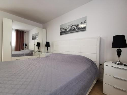 a white bedroom with a bed and a mirror at Villa Lamanova in Rovinj
