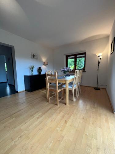 a dining room and living room with a table and chairs at Dom pod klonami in Szczytno