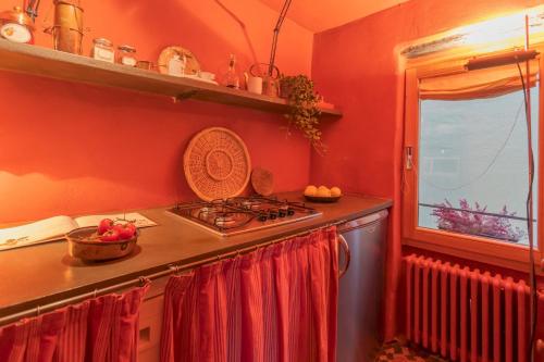 een keuken met rode muren, een fornuis en een raam bij La Corte Degli Artisti by Rent All Como in Blevio