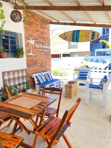 une terrasse avec une table, des chaises et une planche de surf dans l'établissement Pousada Sete Mares, à João Pessoa