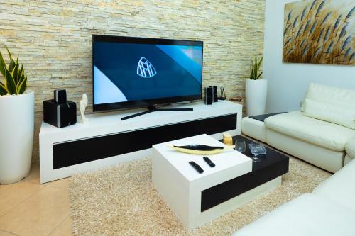 a living room with a tv and a white couch at Hana apartament hot tub in Vlorë