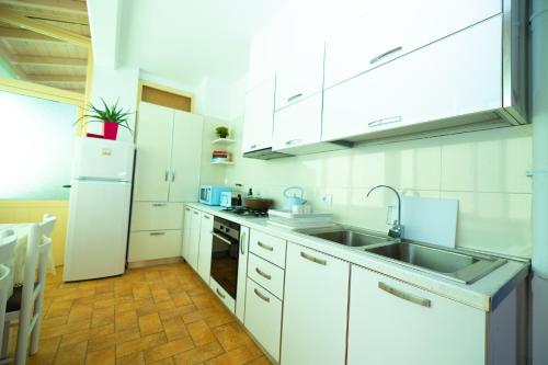 a white kitchen with a sink and a refrigerator at Hana apartament hot tub in Vlorë