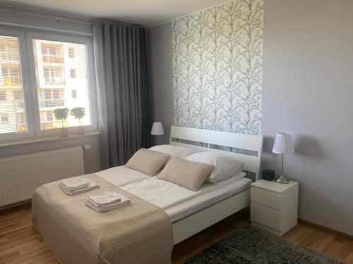 um quarto com uma cama com lençóis brancos e uma janela em IRS ROYAL APARTMENTS Apartamenty IRS Aviator em Gdansk