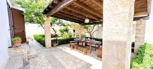 een patio met een houten tafel en banken bij Villa Cigaline in Tiggiano