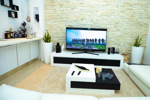 a living room with a flat screen tv on a brick wall at Hana apartament hot tub in Vlorë