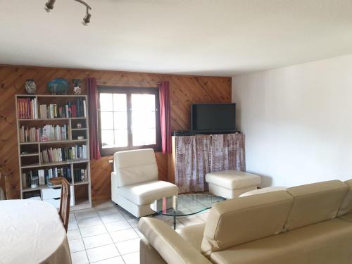 a living room with a couch and chairs and a tv at Les Mélèzes in Val-d'Illiez