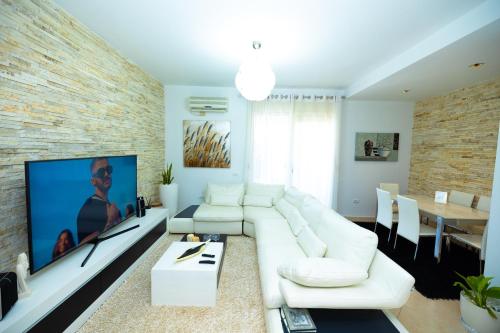 a living room with a white couch and a tv at Hana apartament hot tub in Vlorë