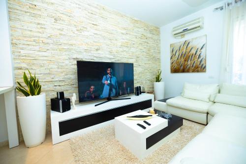a living room with a tv and a brick wall at Hana apartament hot tub in Vlorë