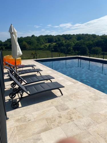 a pool with two lounge chairs and an umbrella at Le Domaine du Gravier in Gramat