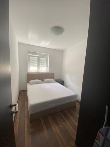 una camera con un letto bianco e una finestra di Ruza apartman a Budua