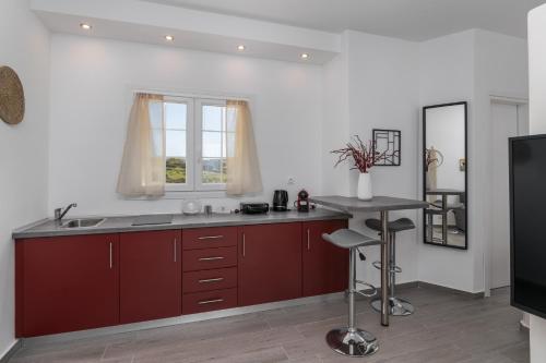 a kitchen with red cabinets and a sink and a table at Sunset Village 3 in Paleochori