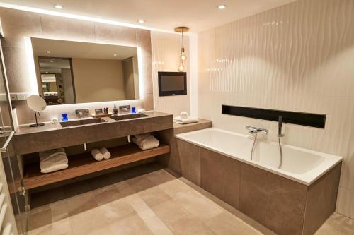 a bathroom with a tub and a sink and a mirror at Steigenberger Hotel Hamburg in Hamburg