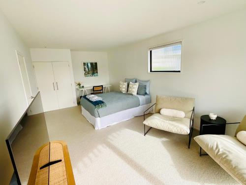a bedroom with a bed and a couch and a chair at Deluxe Downtown Mount Maunganui in Mount Maunganui