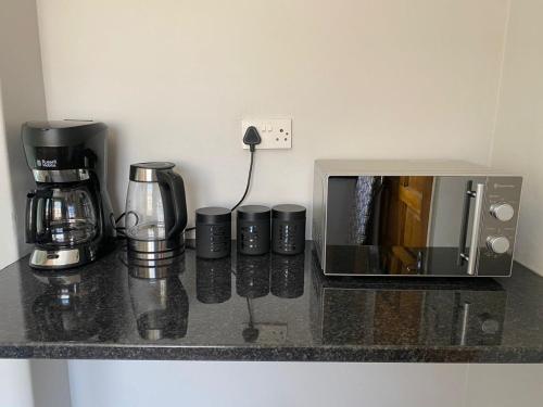 a counter with a coffee maker and cups on it at @20401 in Gaborone