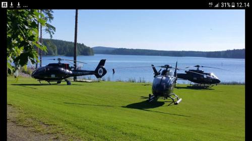 two helicopters parked in a field next to a body of water at Hotelli Viikinhovi in Keuruu