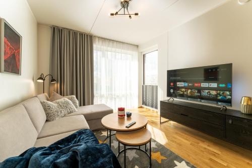 a living room with a couch and a tv at Citygate Sunset balcony in Tartu