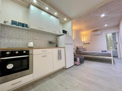 a kitchen with white cabinets and a room with a bed at PassionFruit Arad in Arad