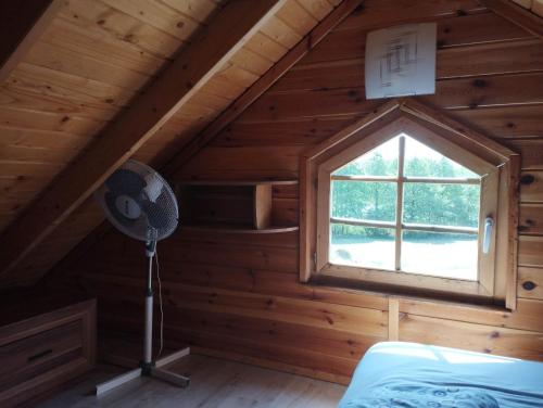 a bedroom in a log cabin with a window at Osada nad żurawim stawem in Krzywogoniec