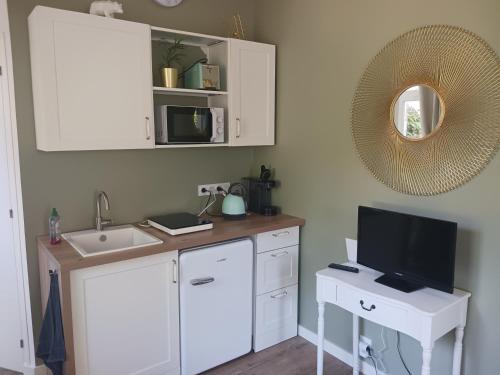 a kitchen with a sink and a desk with a tv at La laiterie de la Plume in Nantes