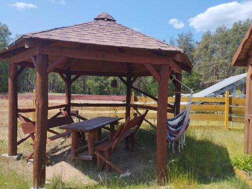 a wooden gazebo with a picnic table and a hammock at Osada nad żurawim stawem in Krzywogoniec