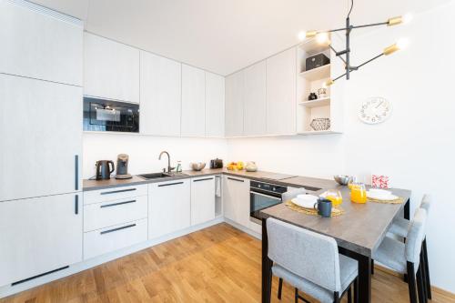 a kitchen with white cabinets and a table with chairs at Citygate Sunset balcony in Tartu