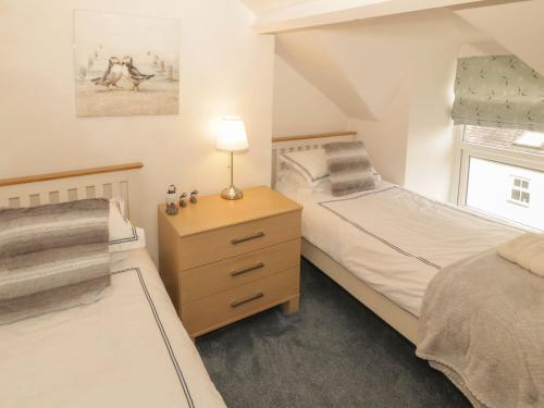a bedroom with two beds and a lamp on a night stand at Harlech View in Criccieth