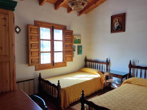 1 dormitorio con 2 camas y ventana en El Cortijuelo de Zalea, en Málaga