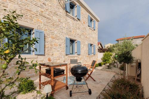a patio with a grill and a table in front of a building at Seafront Villa Adriatica with pool in Dobropoljana
