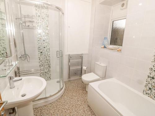 a white bathroom with a toilet and a sink at Bay View in Criccieth