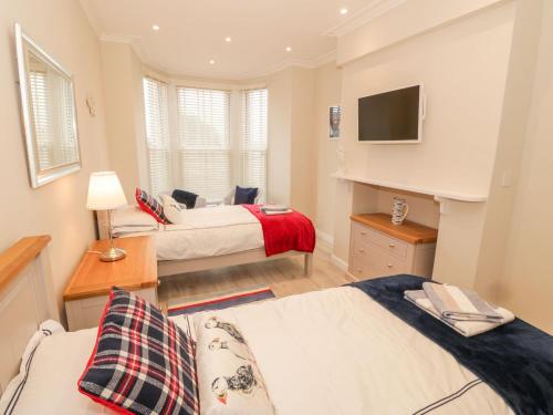 a bedroom with two beds and a tv on the wall at Bay View in Criccieth
