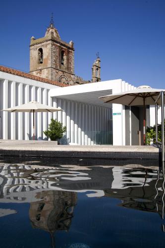 a building with a reflection in a pool of water at Atrio in Cáceres