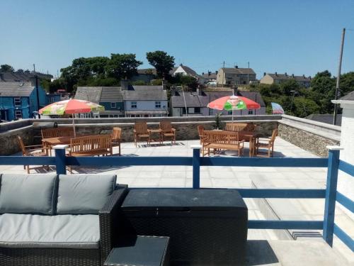 een patio met een bank, tafels en parasols bij Anglesey home by the sea in Amlwch